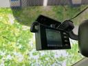 フロントガラス上部に小型の画面付き機器が取り付けられ、視線を大きく動かさず確認しやすい位置です。コンパクトに収まり、運転席まわりの空間を妨げにくい配置となっています。