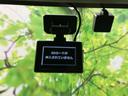 フロントガラス上部に機器が取り付けられ、前方視界を大きく遮りにくい位置に収まっています。画面表示も見えるため、車内装備の配置を確認できるポイントです。