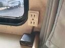 車内側面のコンセントまわりを写した一枚です。窓際に2口コンセントと、下部に電源表示灯付きのソケットが見えます。
